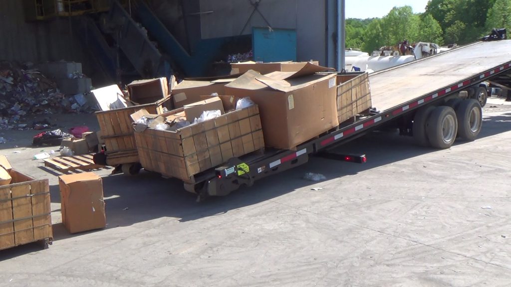 A QuickLoadz trailer is unloading pallets with the tow bar. 