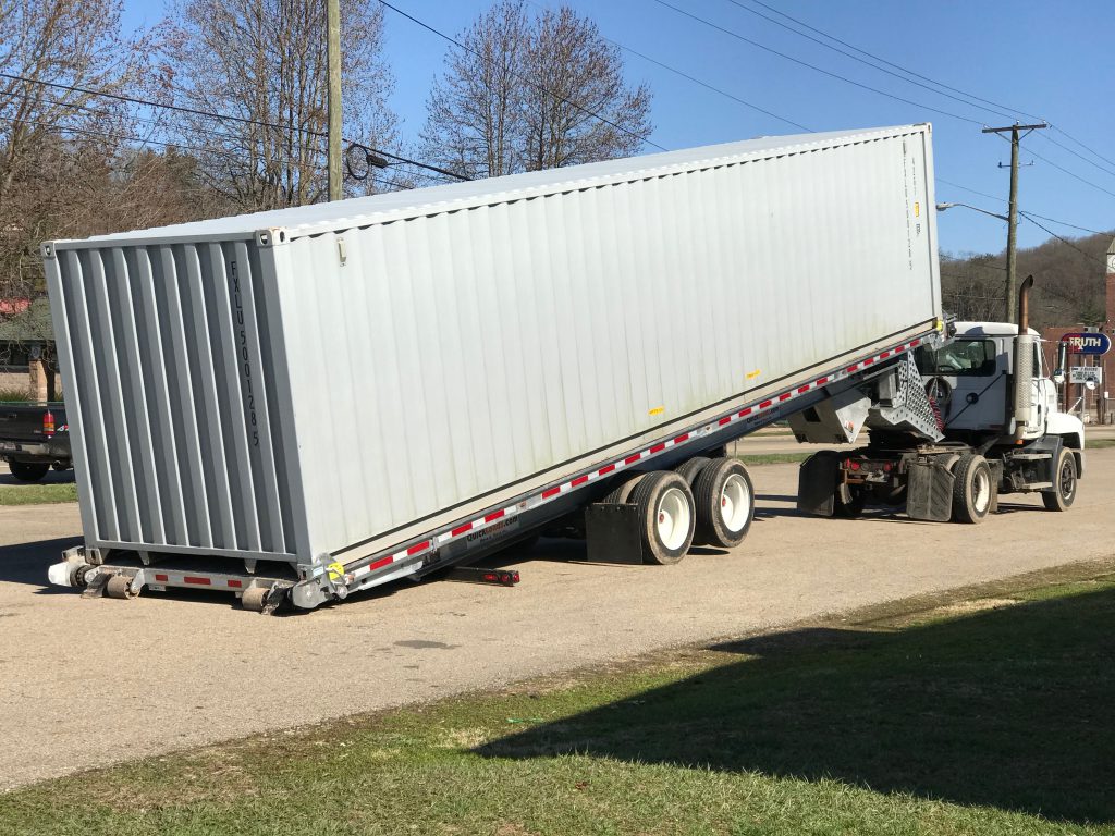 A QuickLoadz automated trailer at an angle with a sea shipping container loaded.