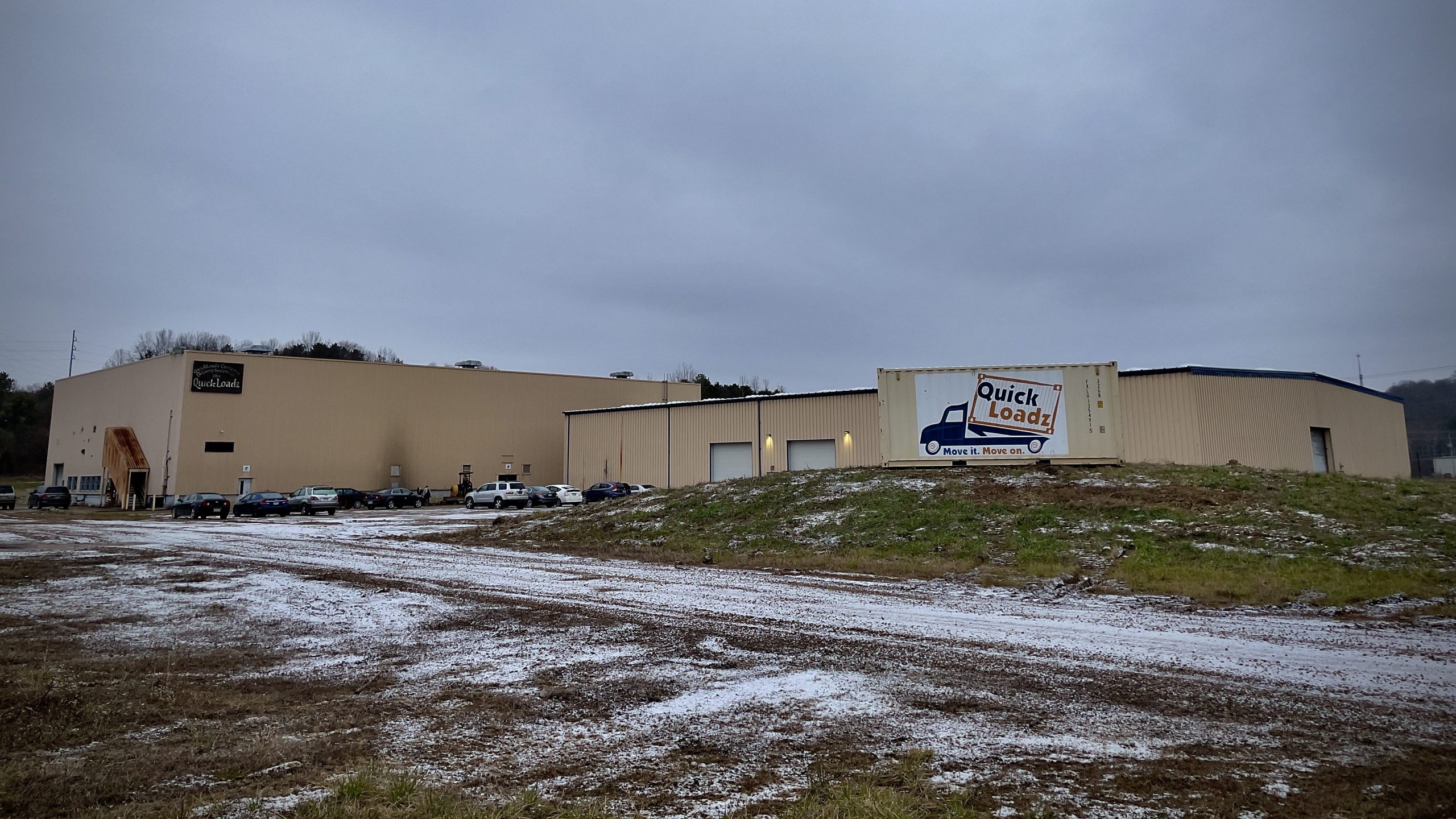 A distance view of the QuickLoadz headquarters with the logo on a container in the foreground.