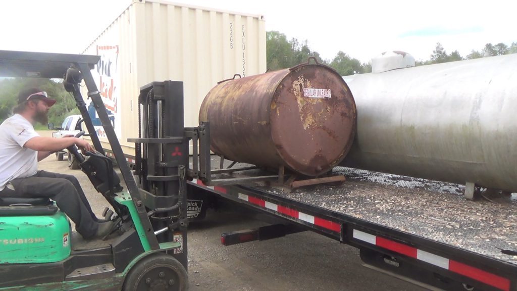 Equipment is being unloaded from the bed of the 26k Super 40 with a forklift. The equipment was loaded behind a 20 foot container.