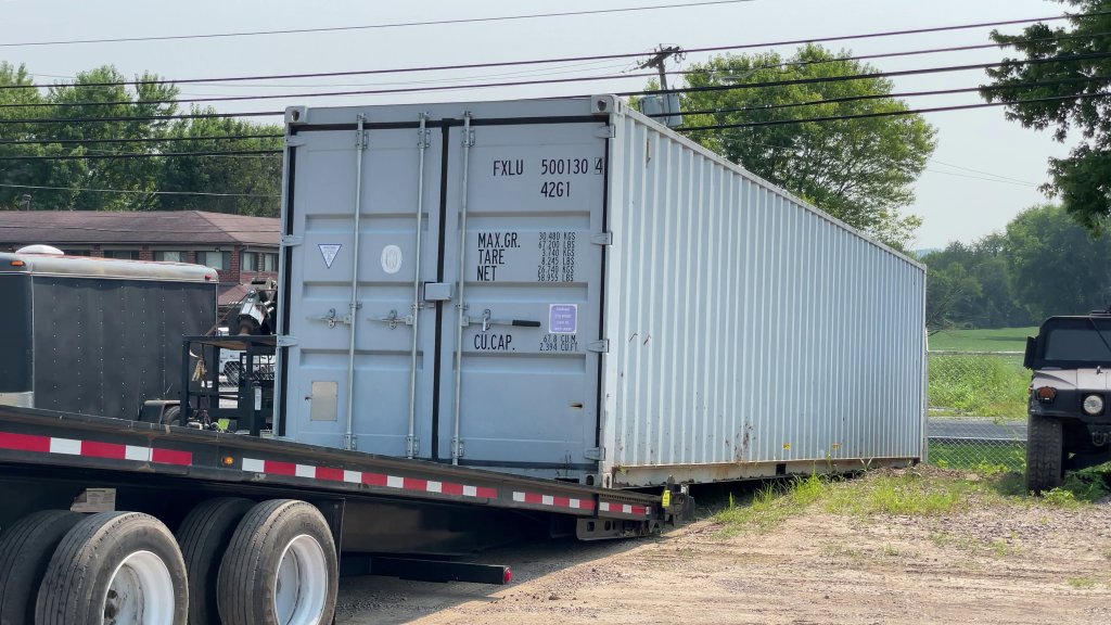 QuickLoadz trailer loading a 40' shipping container in the middle of a parking lot